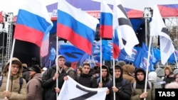 Люди с российскими флагами на площади Ленина в Астрахани во время концерта, посвященного участникам «специальной военной операции» (так Москва называет вторжение в Украину). 22 февраля 2023 года