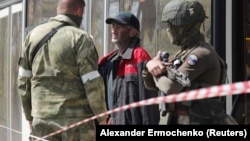 Мужчина, покинувший территорию "Азовстали" в Мариуполе, разговаривает с военнослужащими пророссийских войск возле пункта временного размещения в селе Безыменное Донецкой области, Украина, 1 мая 2022 года