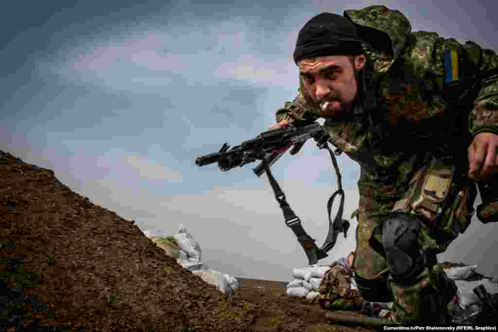 Украинский боец батальона "Азов" пытается укрыться от шквального огня противника. Посело Широкино вблизи Мариуполя. 18 апреля 2015 