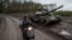 Местный житель едет на скутере мимо подбитого российского танка в Изюме, 14 сентября 2022 года