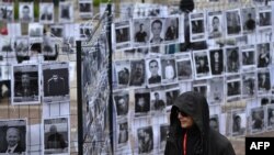 Мужчина проходит мимо портретов белорусских политзаключенных. Уличная выставка в Варшаве. Май 2025 года