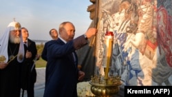 Путин зажигает свечу у мемориала Александру Невскому в Самолве