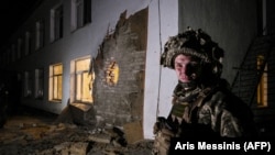 Военнослужащий ВСУ у здания детского сада, поврежденного артиллерийским выстрелом